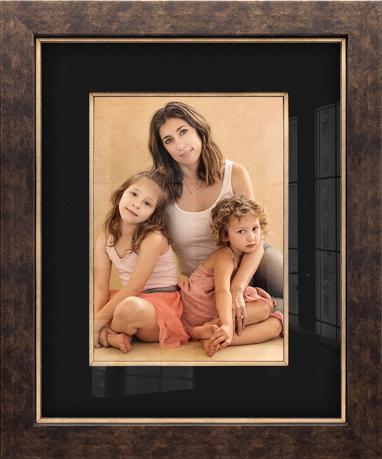 Beautiful family portrait of a young mother and two daughters in an elegant wood frame