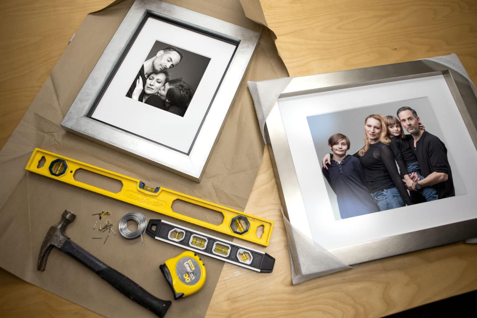 Framed familiy photos on a table with tools, ready to be hung