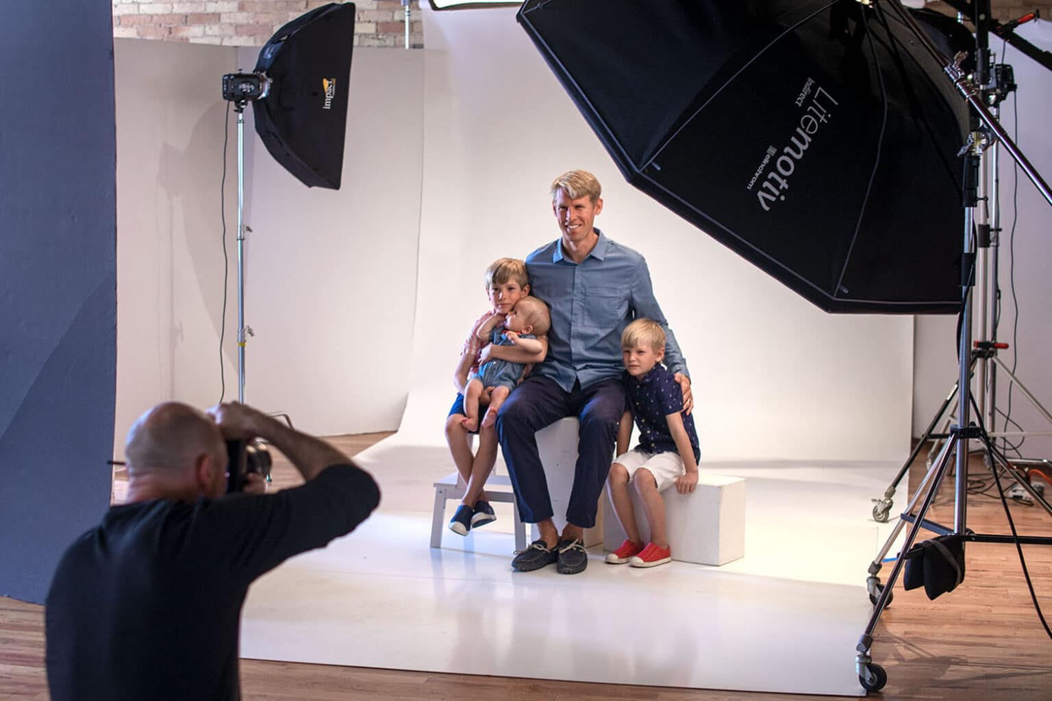 behind the scenes: photographer taking picture of a father and sons in a studio